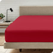 A bed with a microfiber fitted sheet on the mattress. 