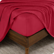 A corner of a mattress with a fitted sheet and a flat sheet on it.