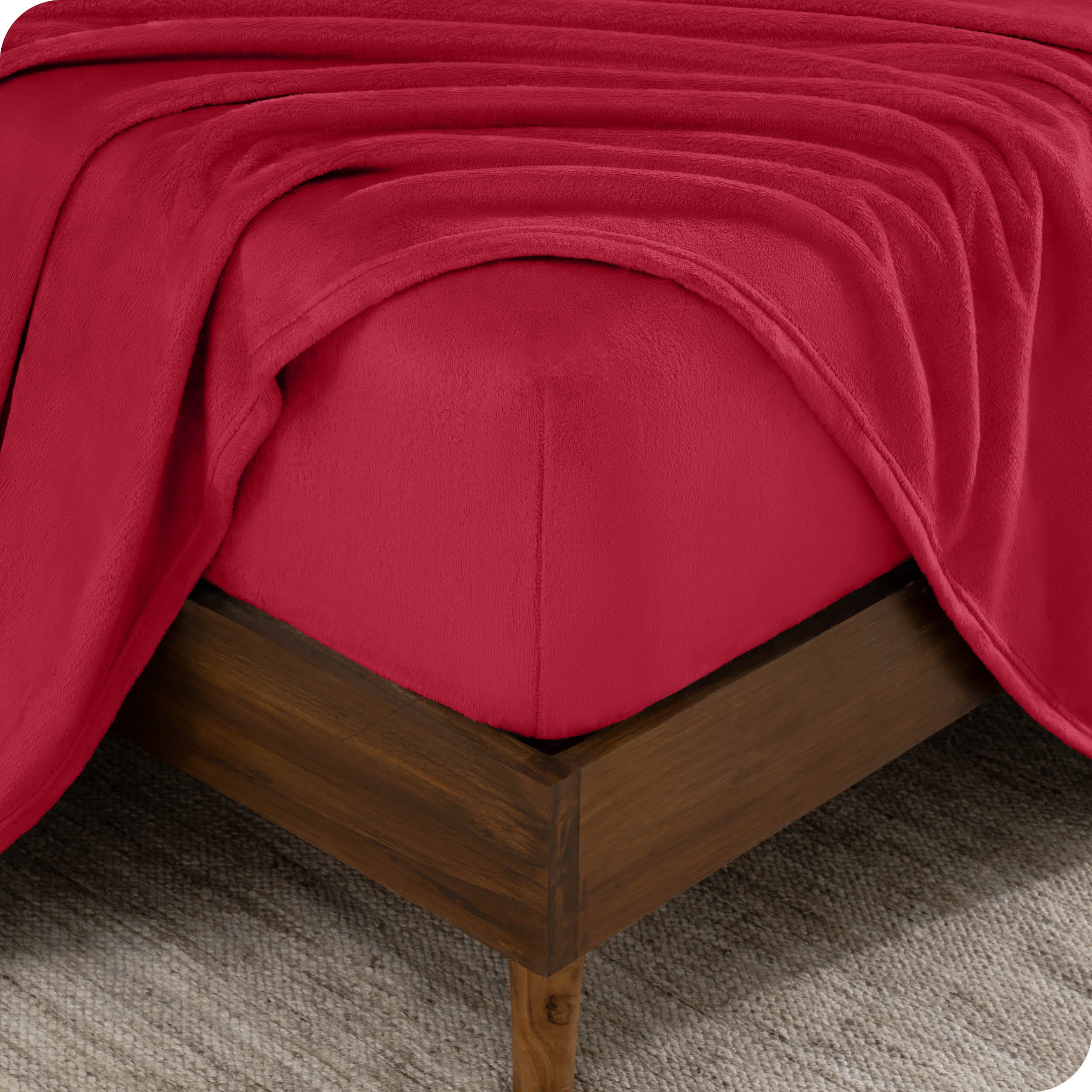 A corner of a mattress with a fitted sheet and a flat sheet on it.