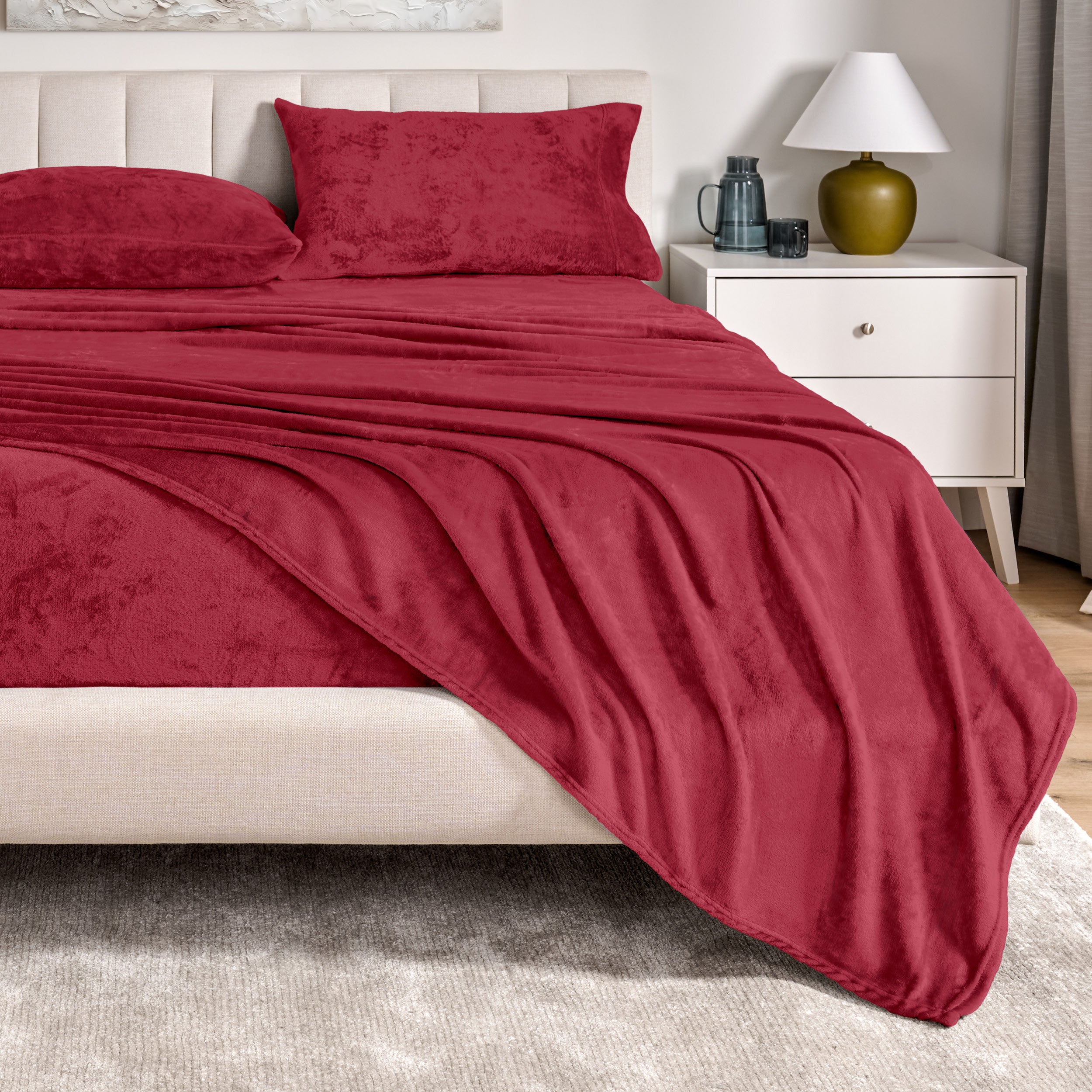 Microplush sheets on a bed in a bedroom setting with a nightstand and lamp.