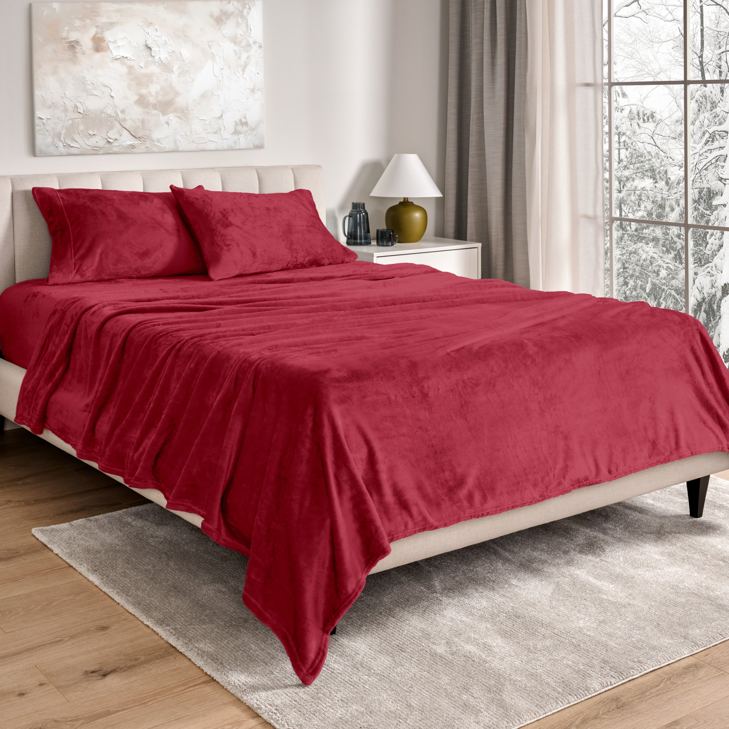 Sheets and matching pillowcases on a bed in a bedroom with a lamp and window in the background.
