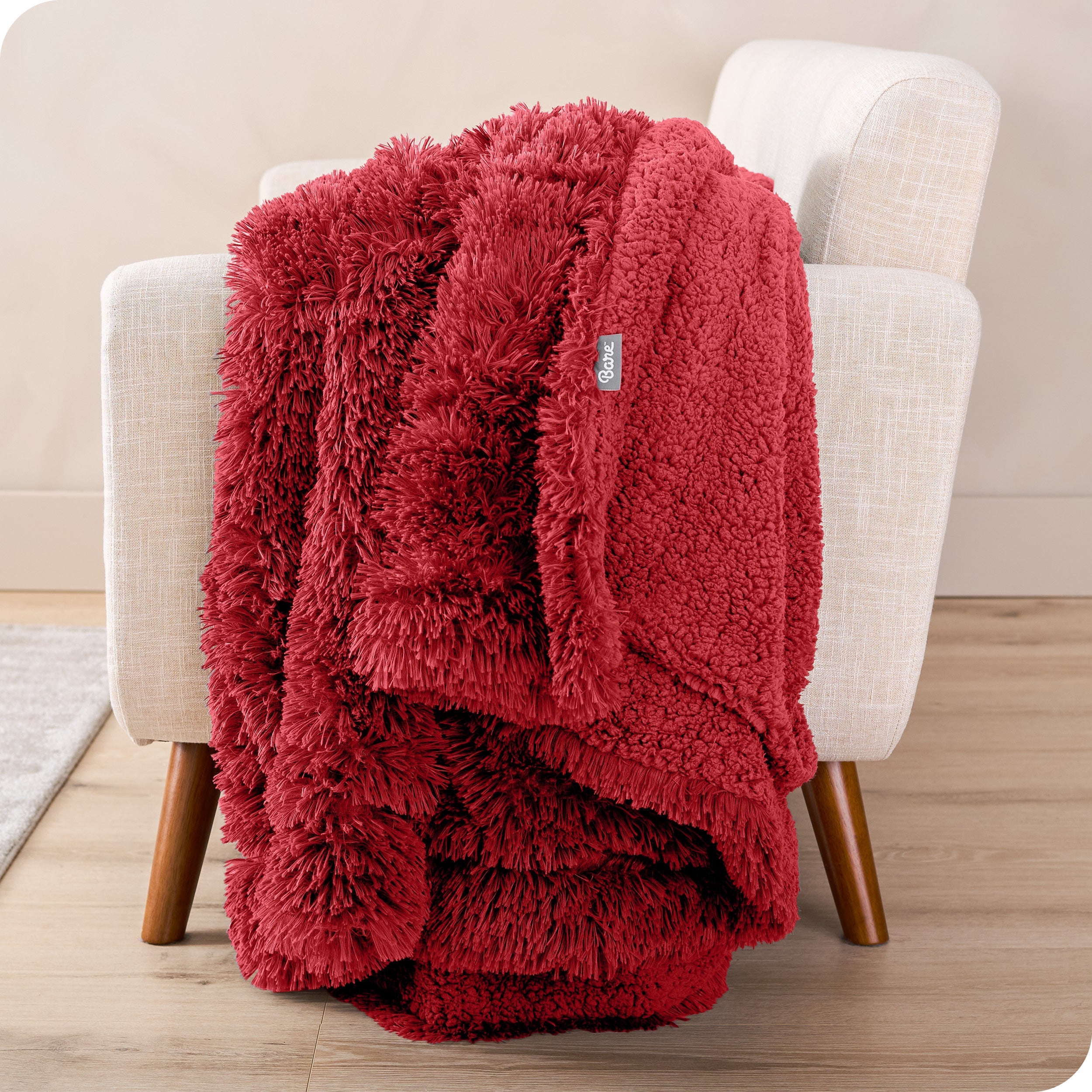 A shaggy faux fur blanket draped over the arm of a chair