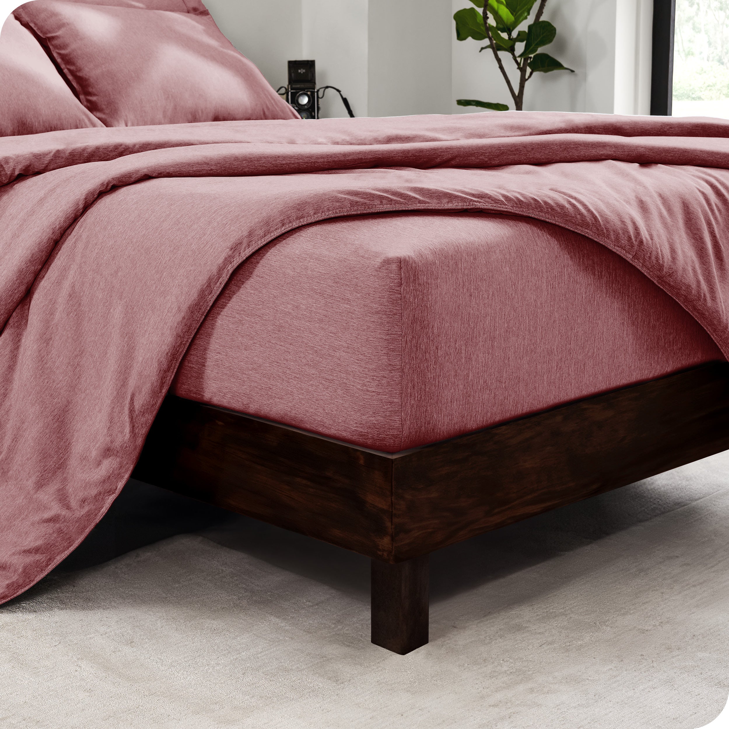 The corner of a mattress with a fitted sheet and comforter on it