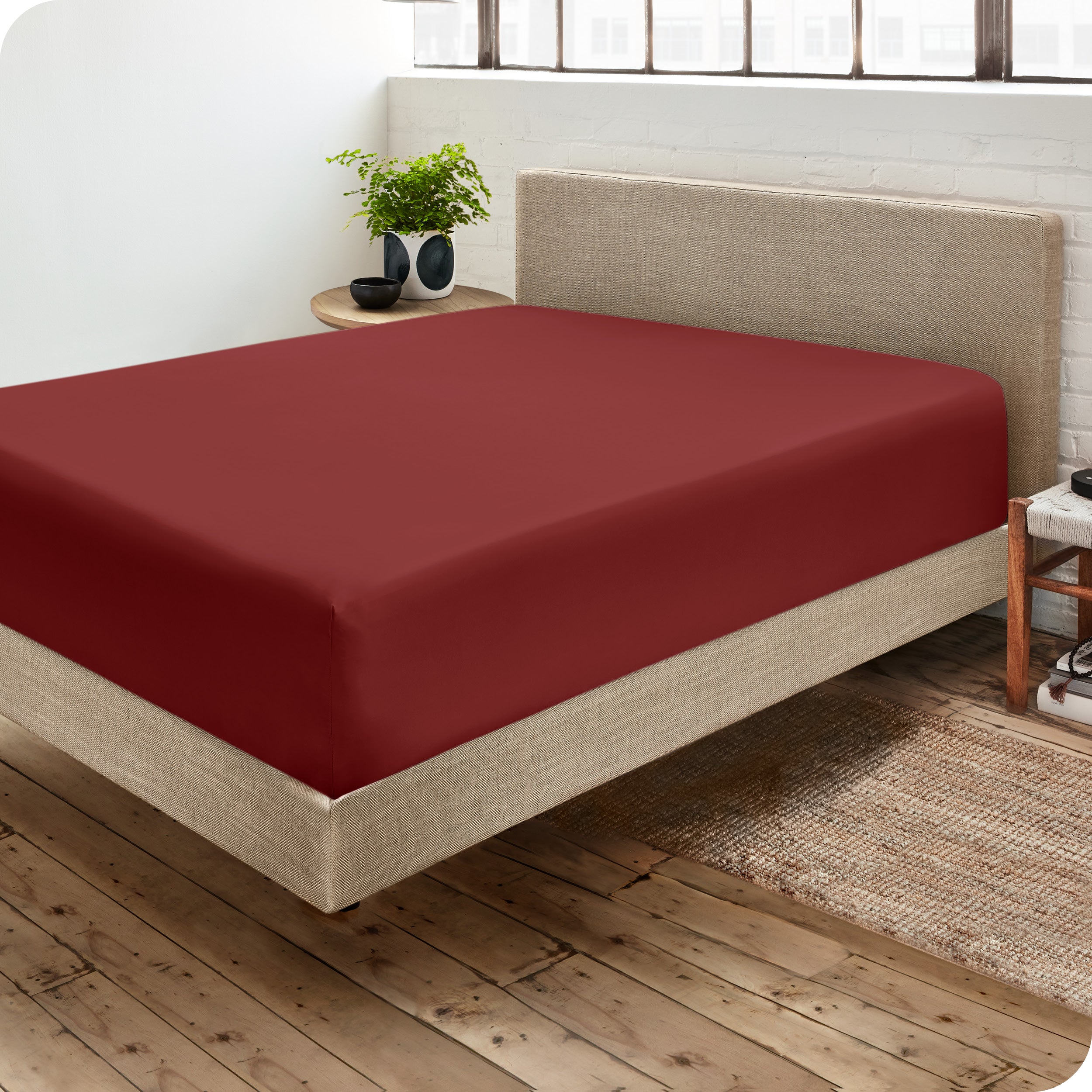 Corner view of a modern bed with a microfiber fitted sheet on the mattress. 