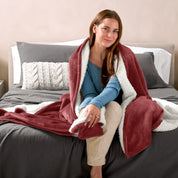 Woman cuddling with a sherpa blanket while sitting on the end of a bed