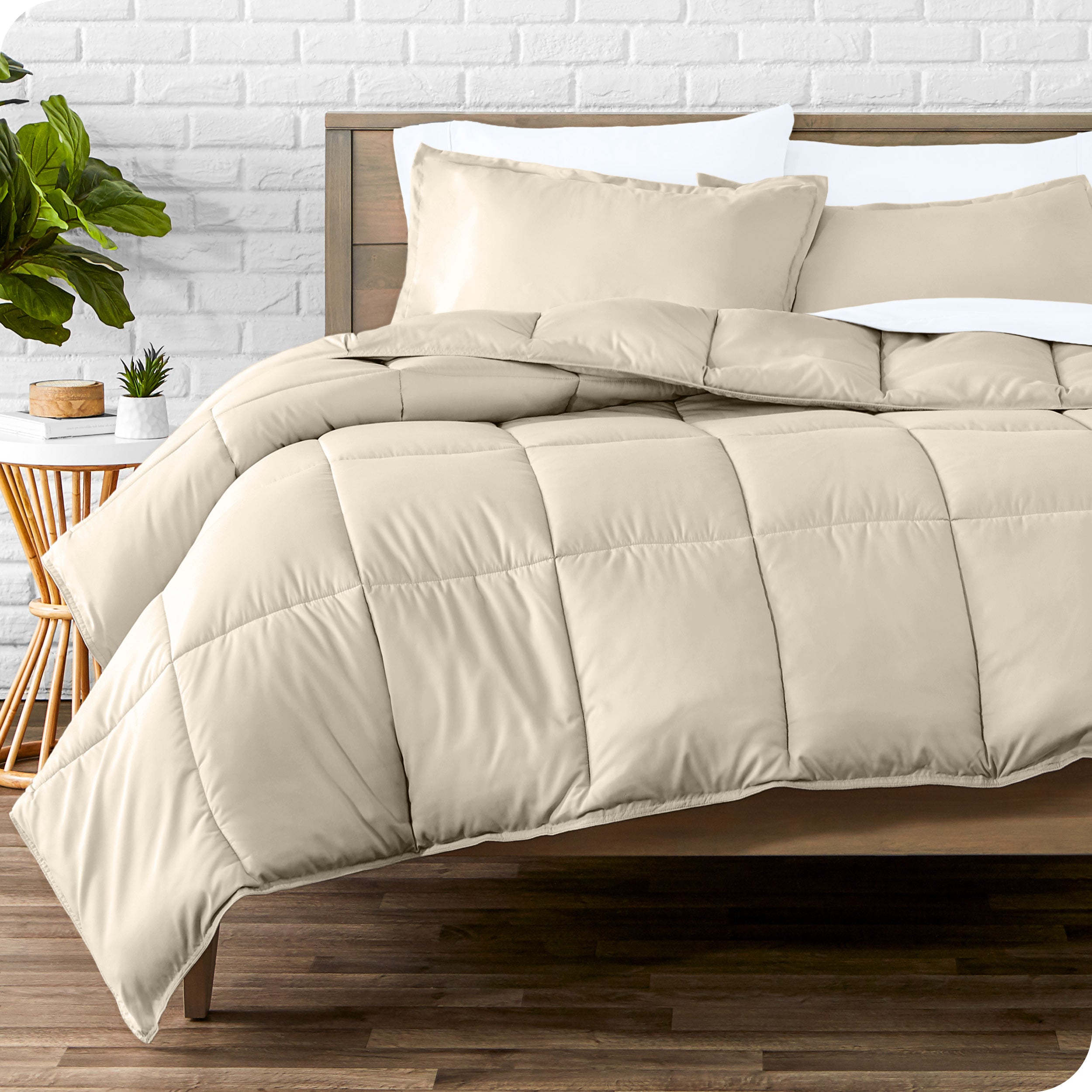 A wooden bed frame with sheets, pillow shams and a comforter on the bed