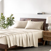 Modern bedroom with a bed against a white wall with a nightstand next to the bed. The bed has bamboo sheets draped over it.