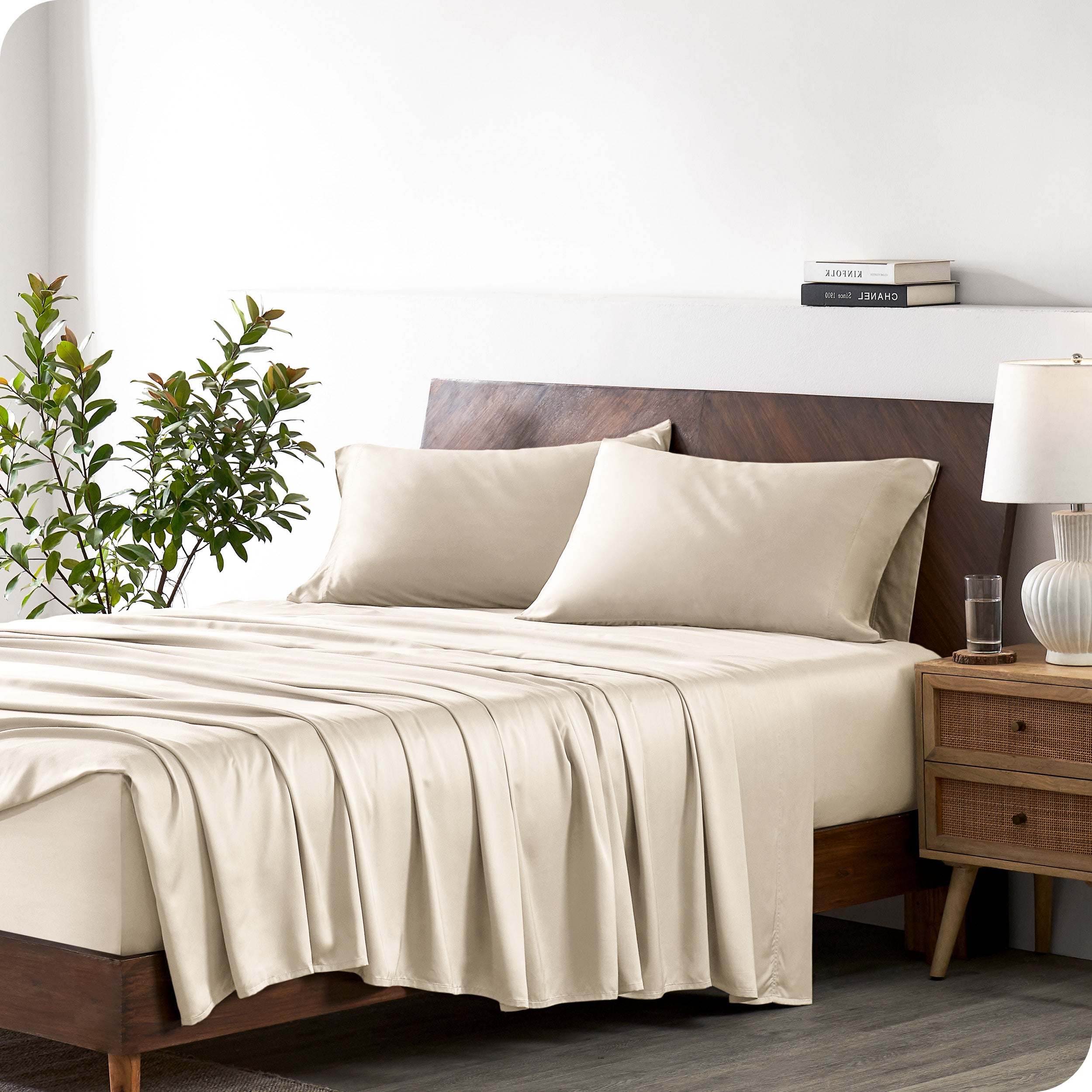Modern bedroom with a bed against a white wall with a nightstand next to the bed. The bed has bamboo sheets draped over it.