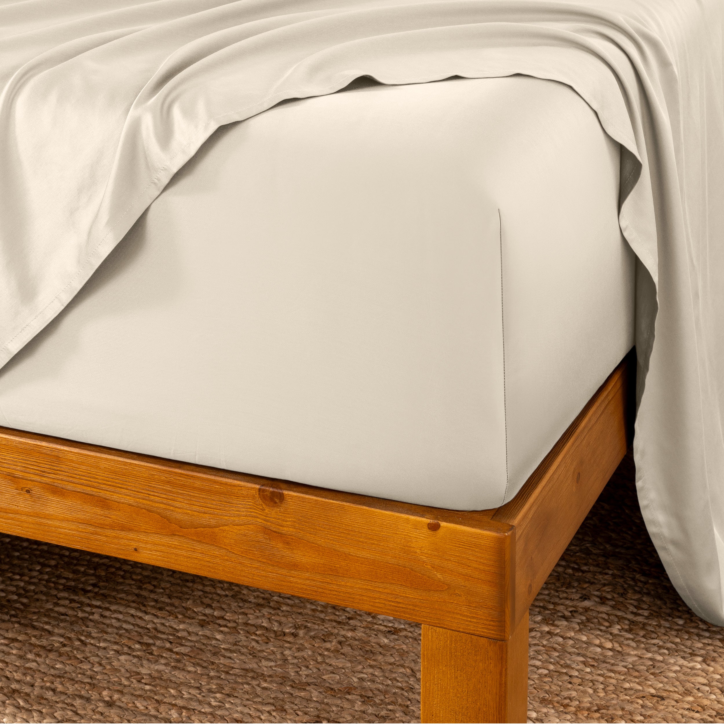 Bed sheets on a wooden bed frame with a brown carpet background