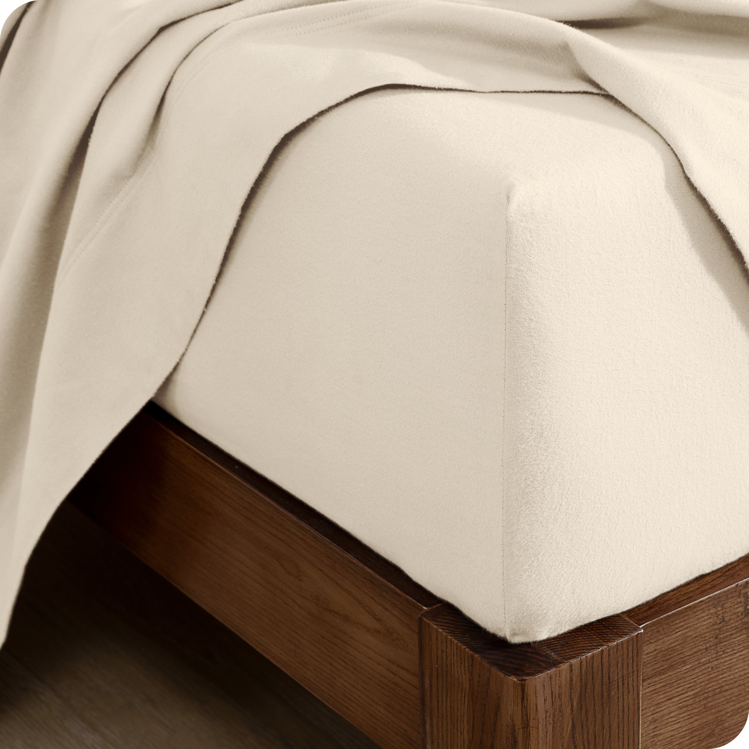 Close up of the corner of a mattress with a fitted sheet and flat sheet on it
