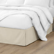 The corner of a bed with a bed skirt and comforter on it
