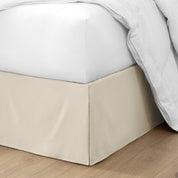 The corner of a bed with a bed skirt and comforter on it