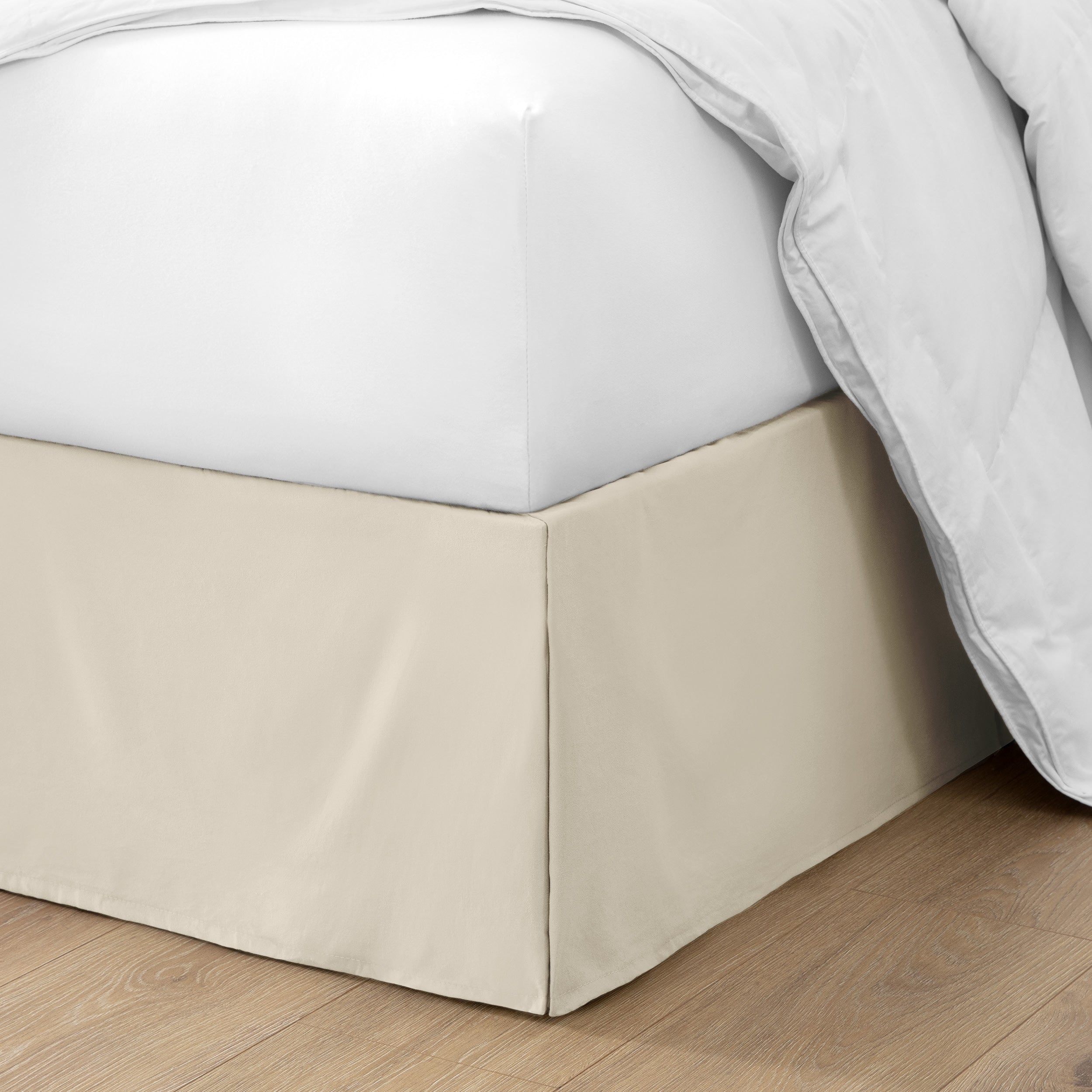 The corner of a bed with a bed skirt and comforter on it