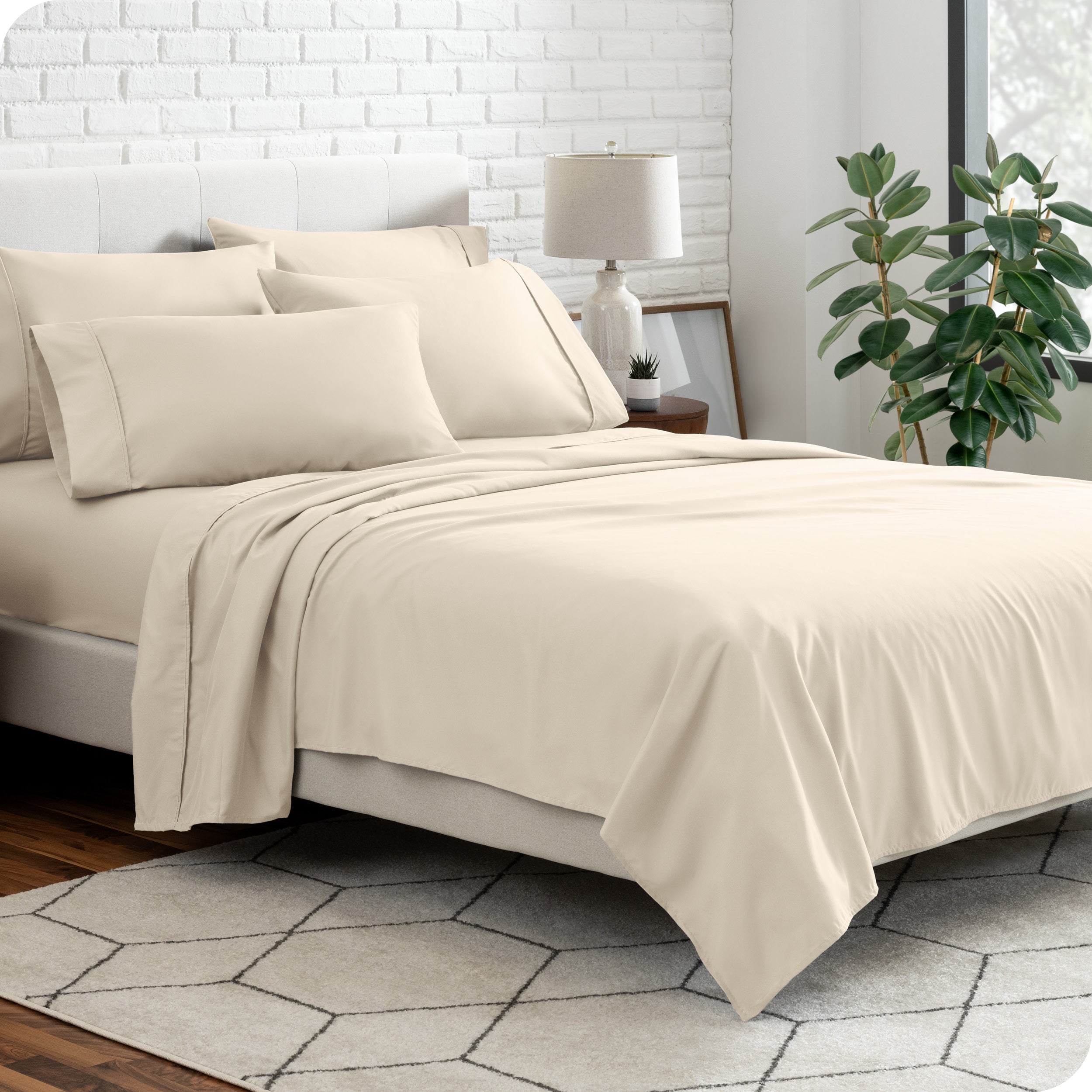 A bedroom setting with a bed made with the microfiber bed sheets and four pillows.