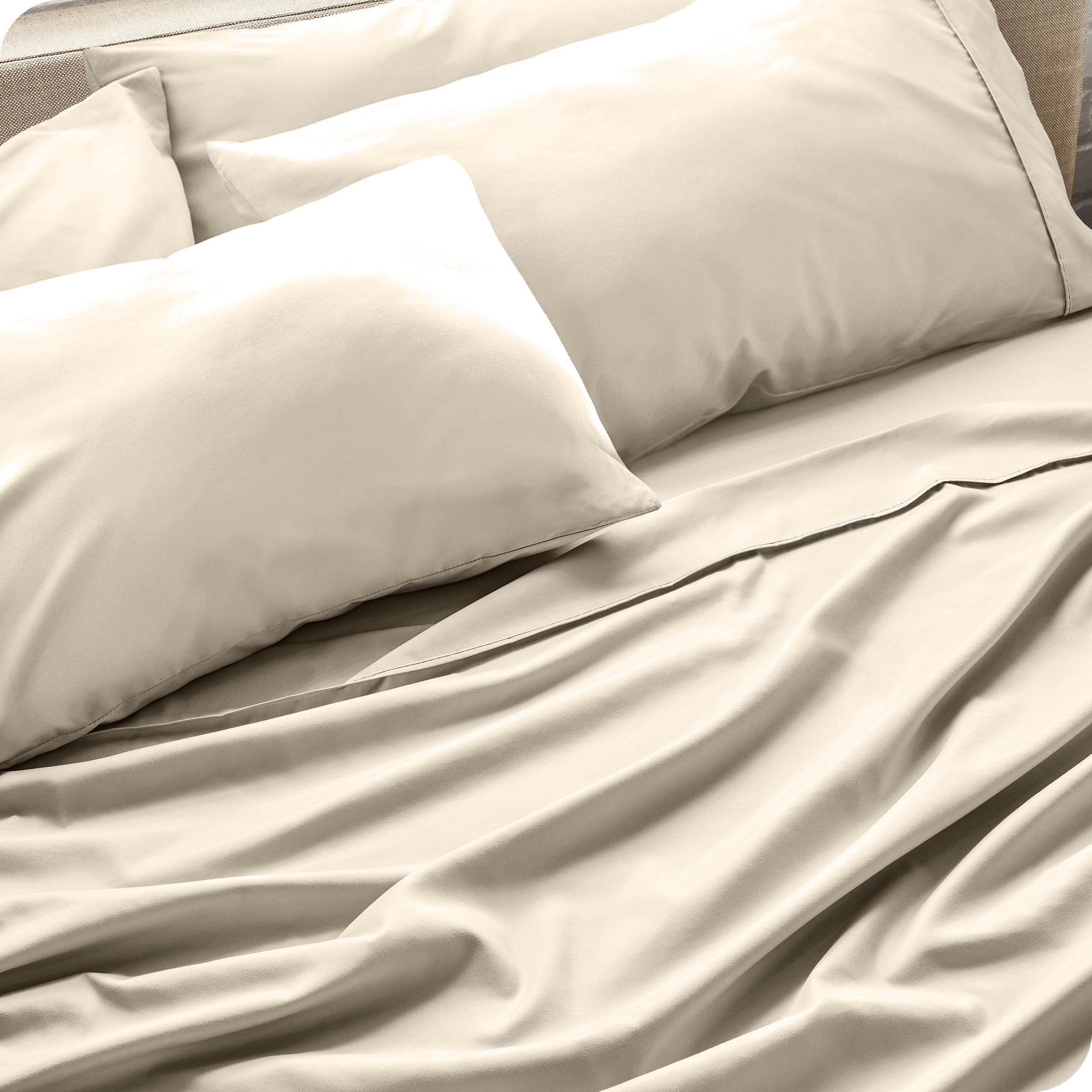 Close up of the microfiber bed sheets on a bed with four pillows.