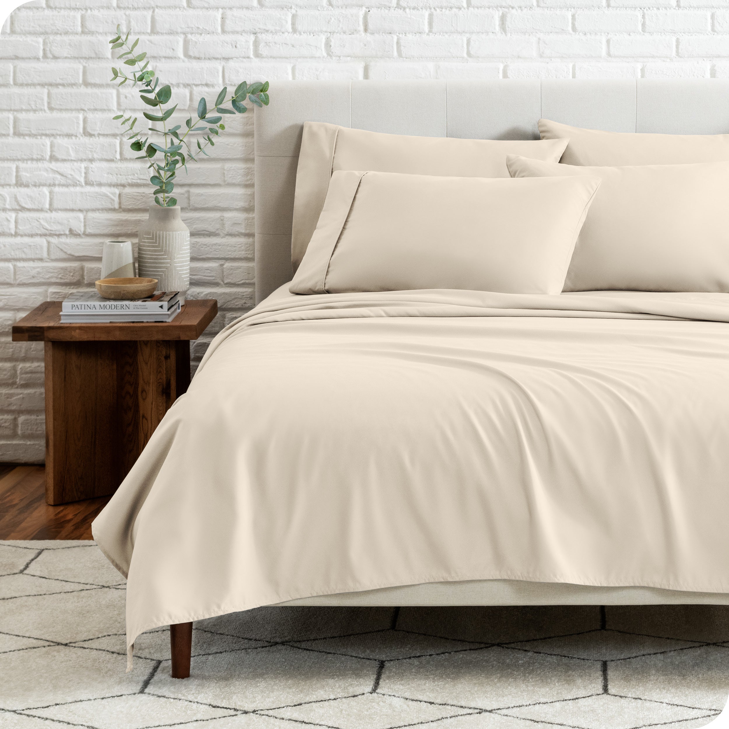 End view of a modern bed with the microfiber sheets on the bed with four pillows.