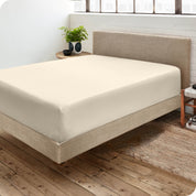 Corner view of a modern bed with a microfiber fitted sheet on the mattress. 