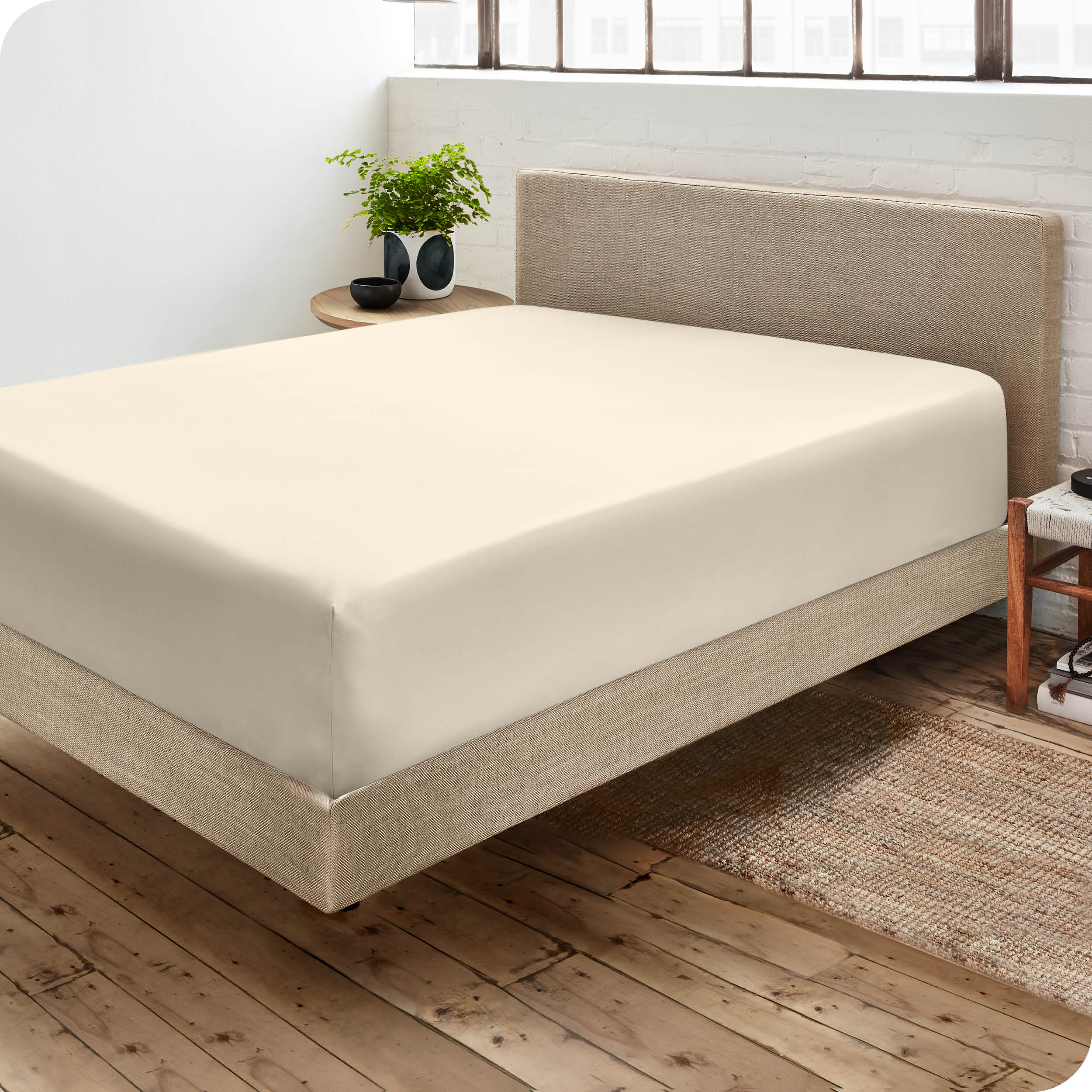 Corner view of a modern bed with a microfiber fitted sheet on the mattress. 