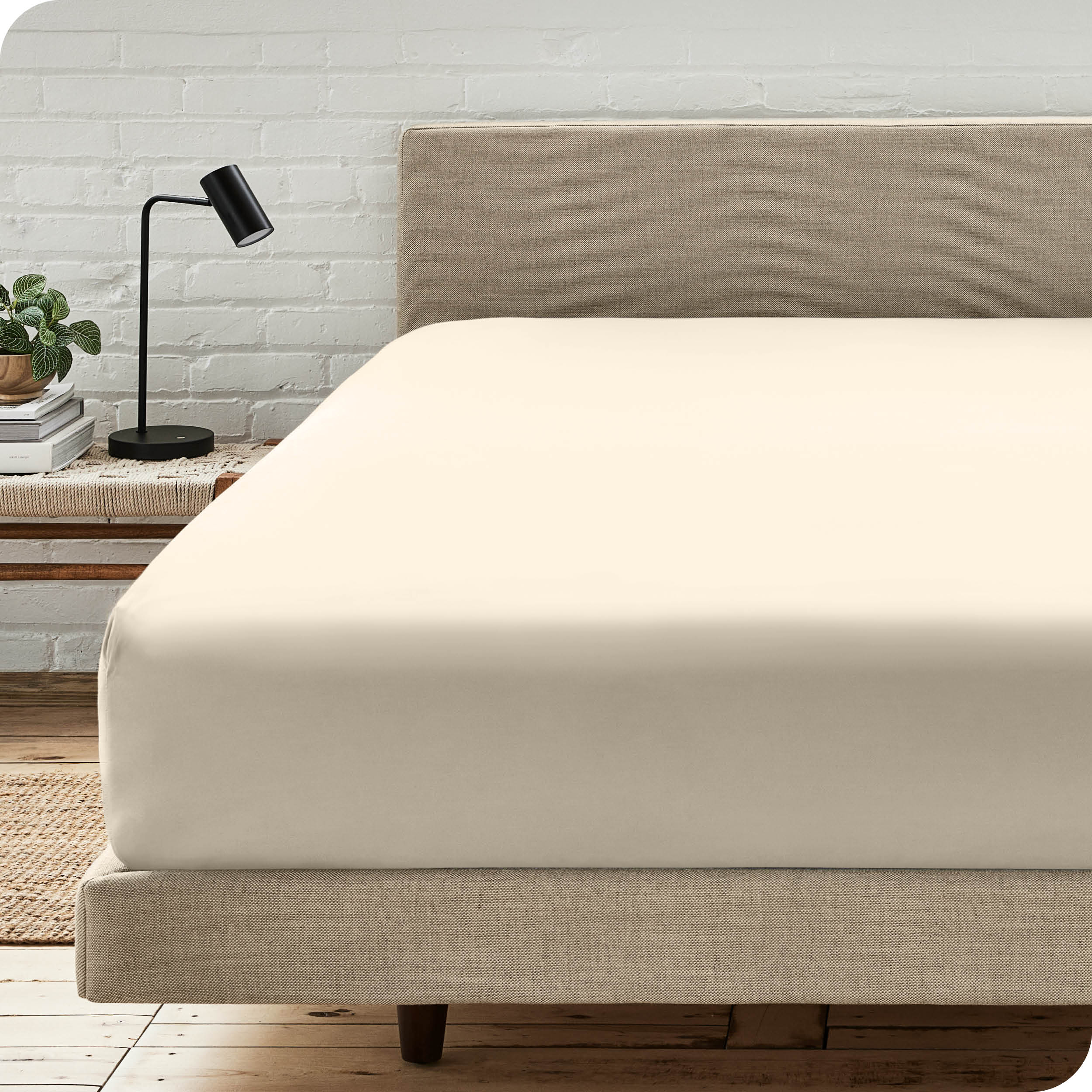 A bed with a microfiber fitted sheet on the mattress. 