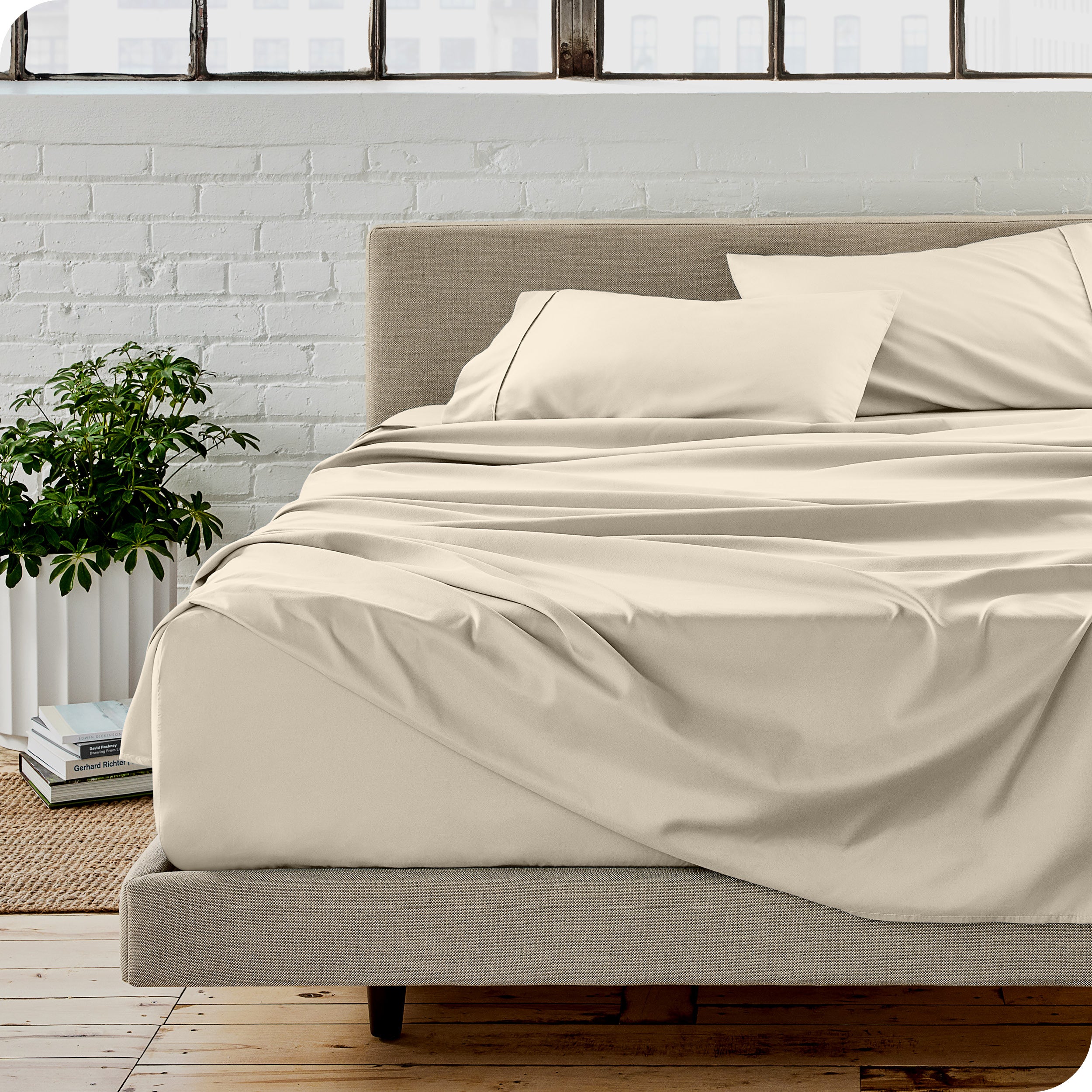 Microfiber sheets on a bed with a brick wall behind it