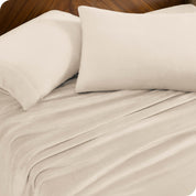 Two pillows with pillowcases on them set on a bed with matching sheets