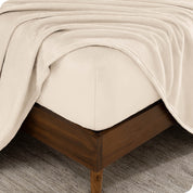 A corner of a mattress with a fitted sheet and a flat sheet on it.