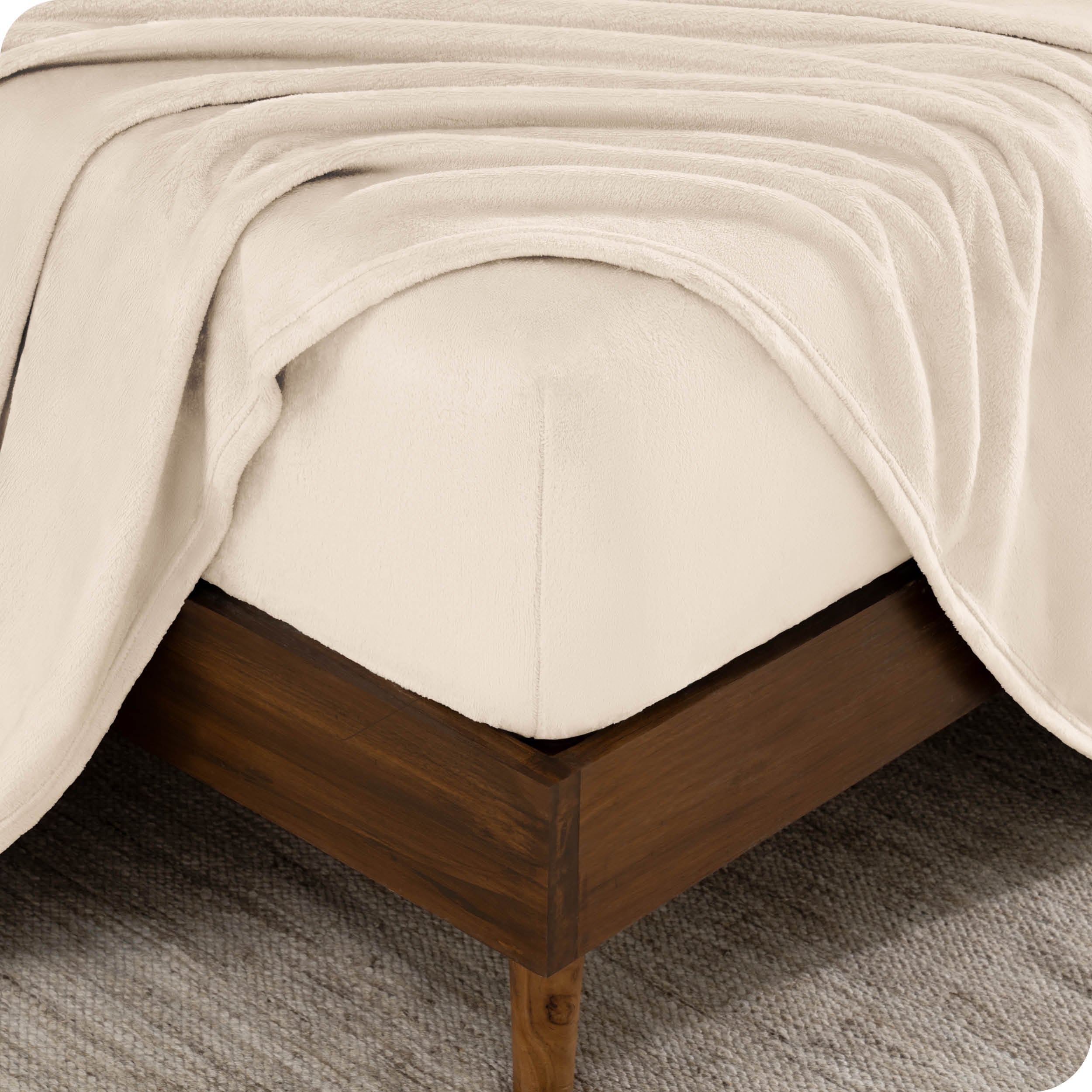 A corner of a mattress with a fitted sheet and a flat sheet on it.