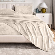 Microplush sheets on a bed in a bedroom setting with a nightstand and lamp.