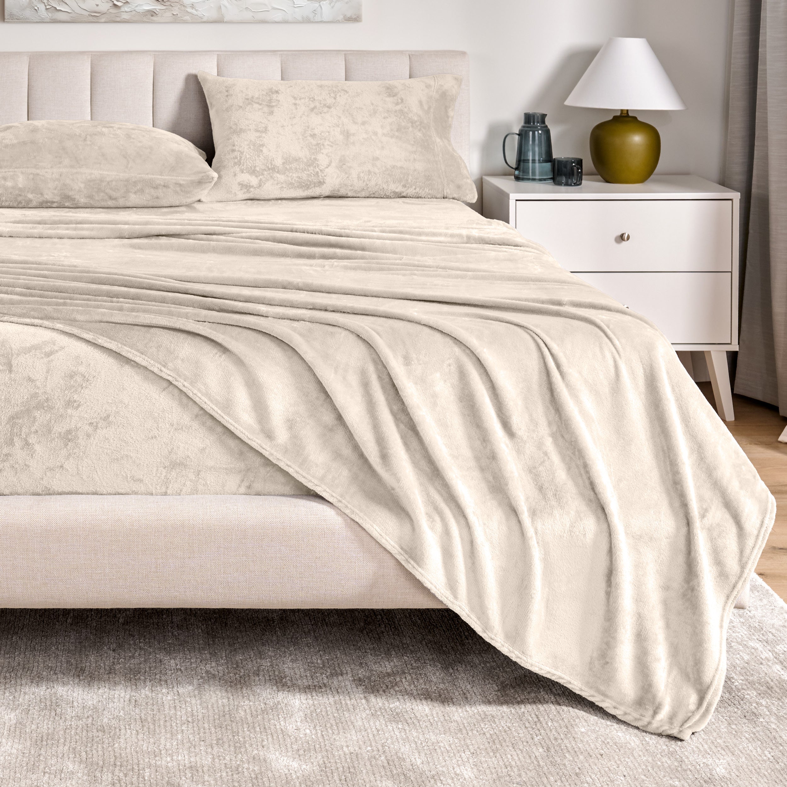 Microplush sheets on a bed in a bedroom setting with a nightstand and lamp.