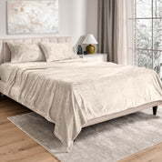 Sheets and matching pillowcases on a bed in a bedroom with a lamp and window in the background.