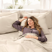 A woman sleeping on a bed made with organic cotton sateen sheets and pillowcases