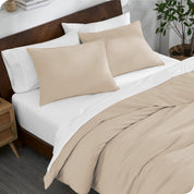 A bed made with an organic jersey duvet cover, pillow sham covered pillows and extra pillows