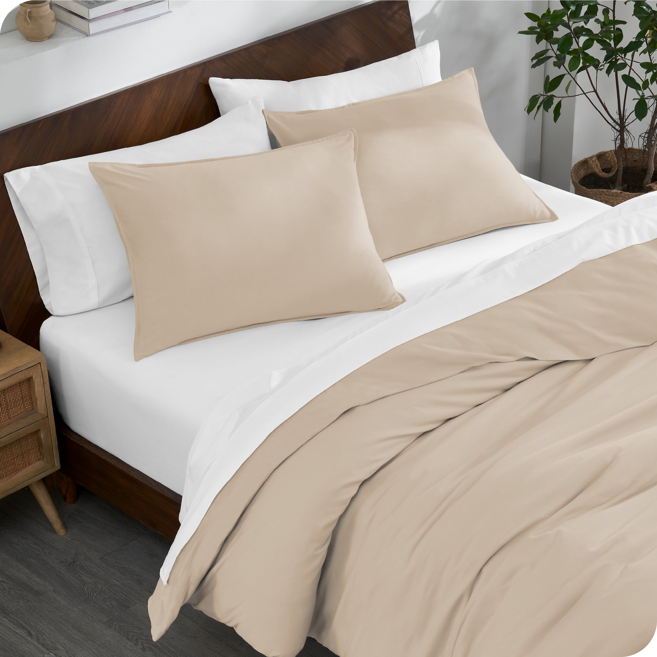 A bed made with an organic jersey duvet cover, pillow sham covered pillows and extra pillows
