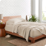 Organic jersey sheets on a bed with a brick wall behind the headboard