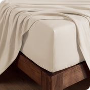 Close up of the corner of a mattress with a fitted sheet and flat sheet on it