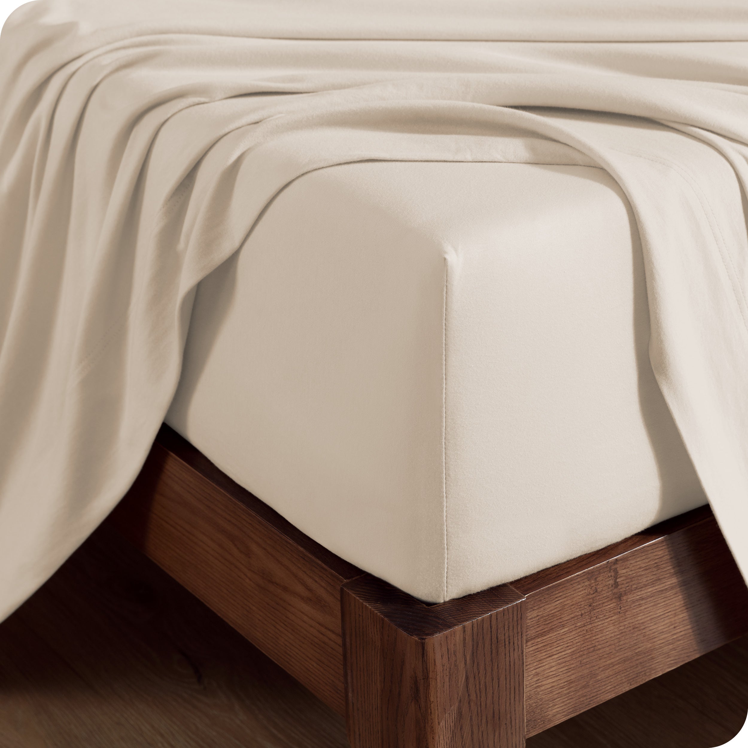 Close up of the corner of a mattress with a fitted sheet and flat sheet on it