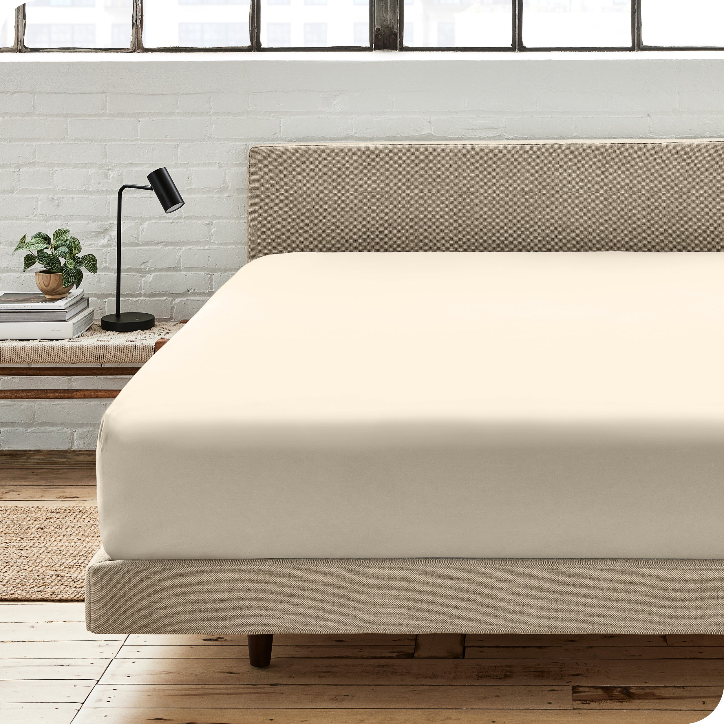 A percale fitted sheet on a bed with table next to it