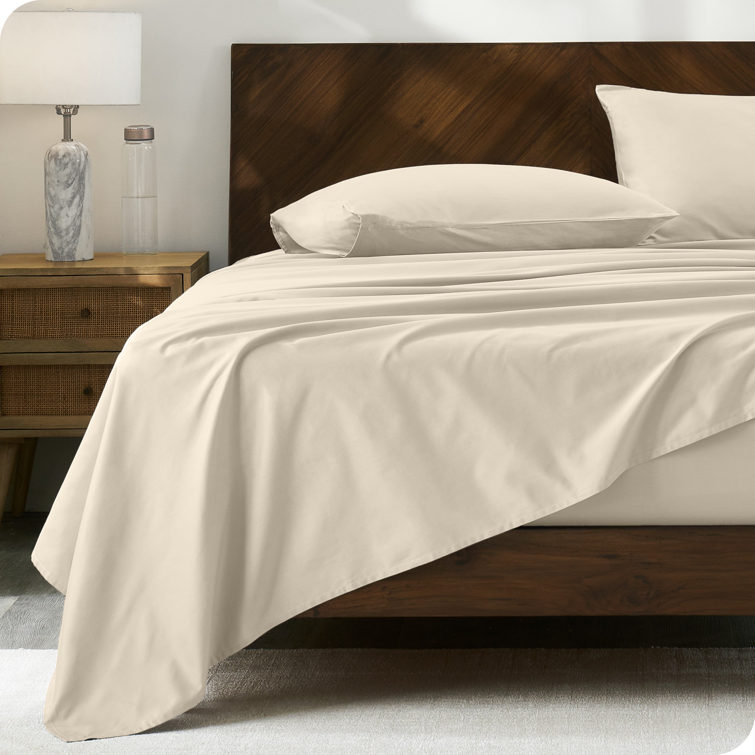 Percale sheet set on a bed with a wooden headboard