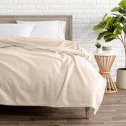 A polar fleece blanket on a bed next to a table and a large plant