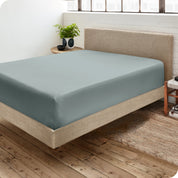 Corner view of a modern bed with a microfiber fitted sheet on the mattress. 