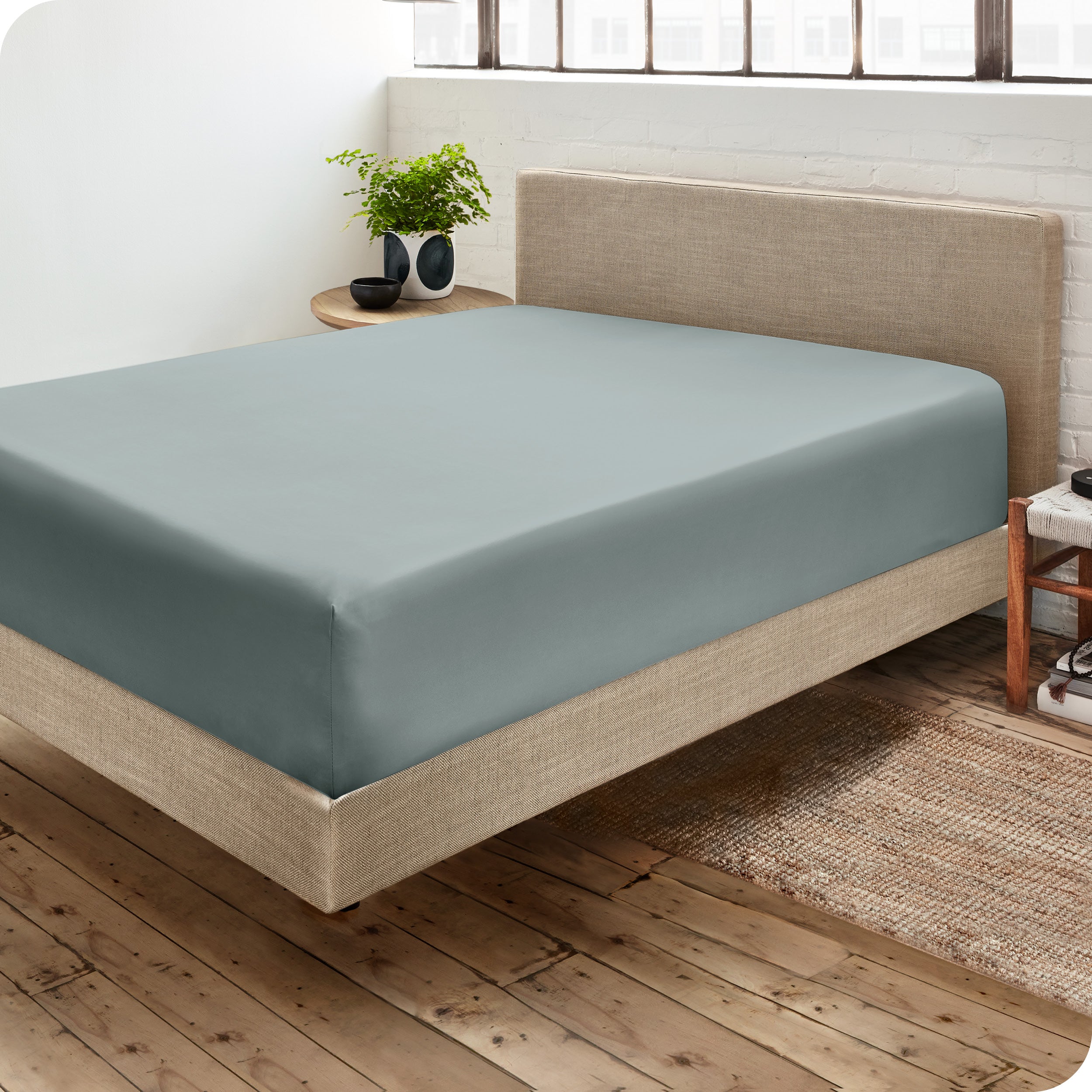 Corner view of a modern bed with a microfiber fitted sheet on the mattress. 