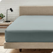 A bed with a microfiber fitted sheet on the mattress. 