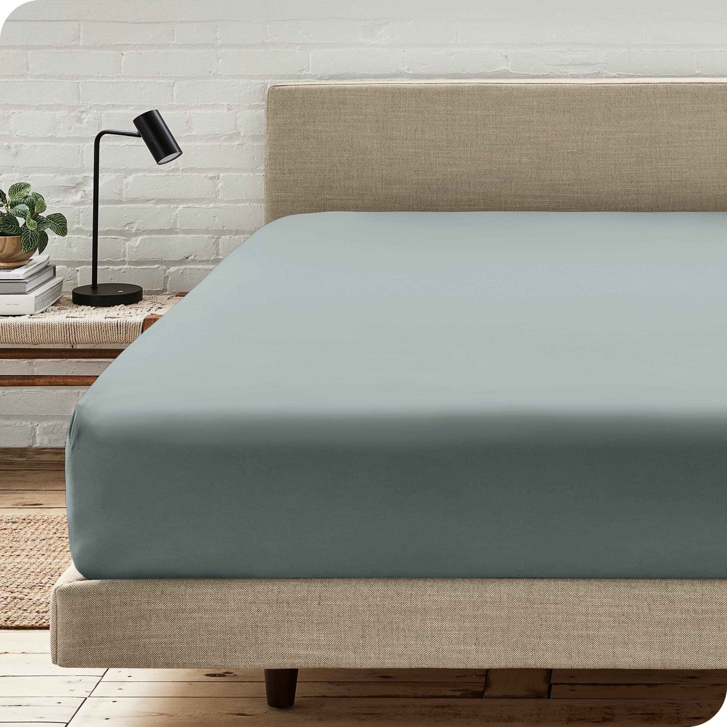 A bed with a microfiber fitted sheet on the mattress. 