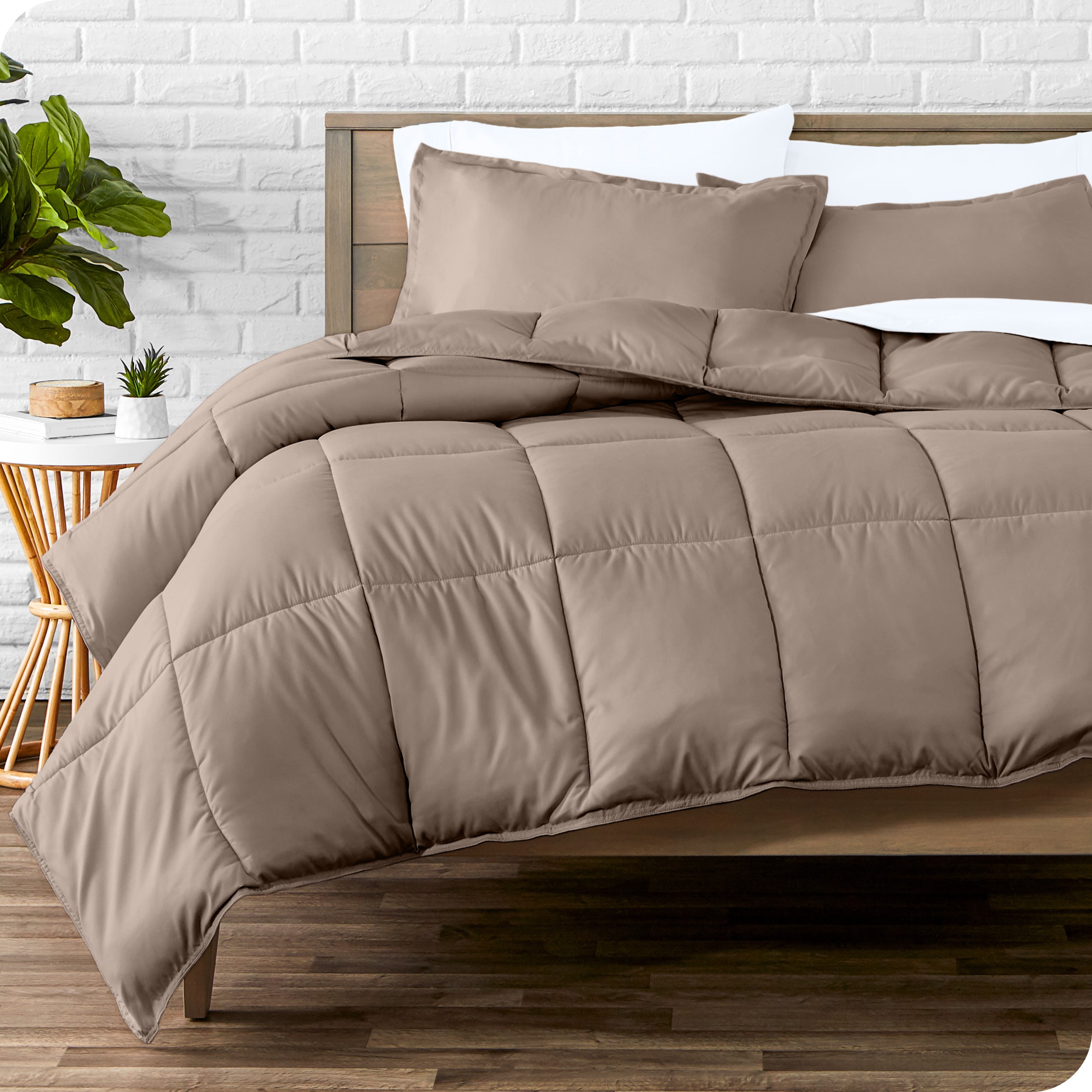 A wooden bed frame with sheets, pillow shams and a comforter on the bed