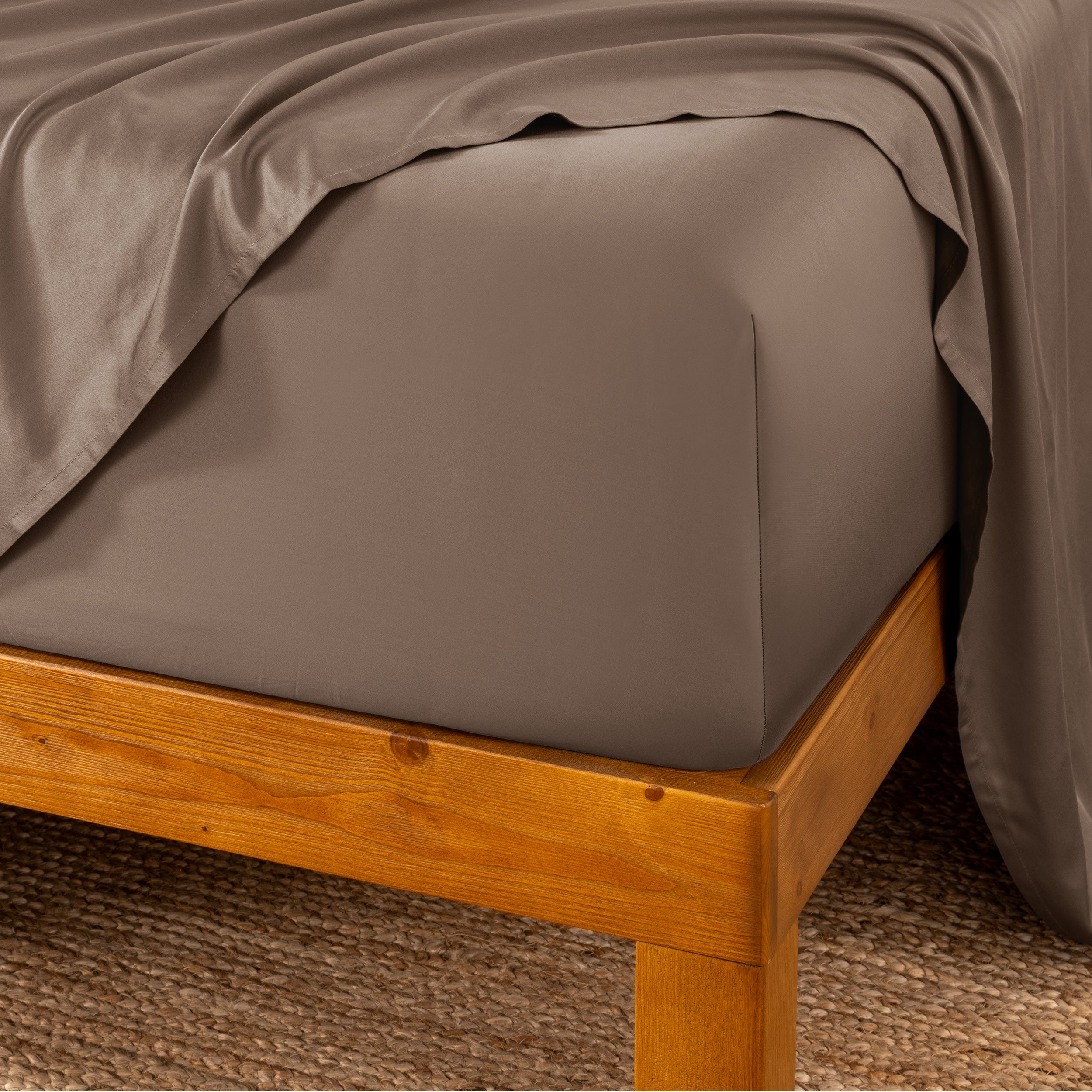 Bed sheets on a wooden bed frame with a brown carpet background