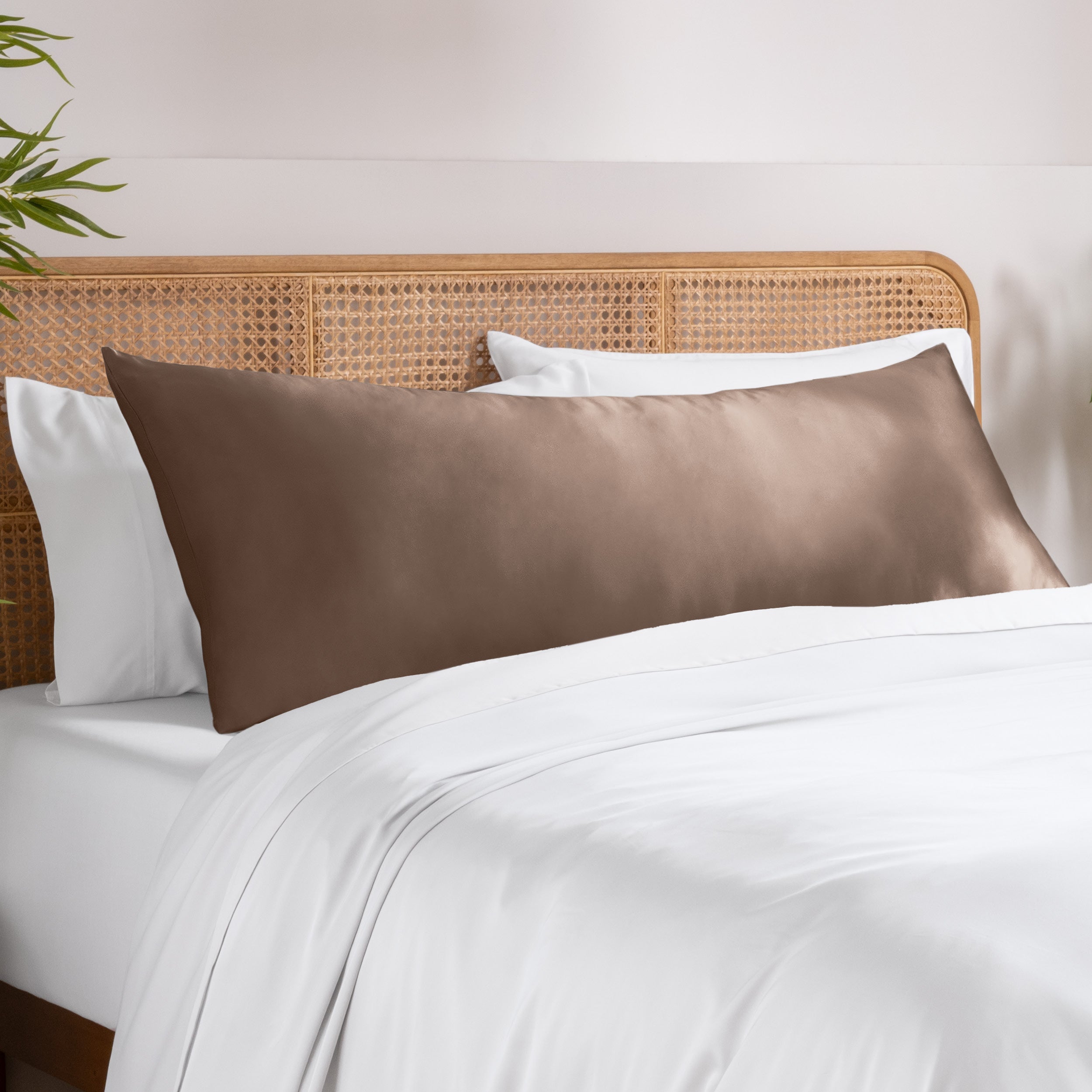 Bamboo pillowcase on a bed with white bedding and a wooden headboard.