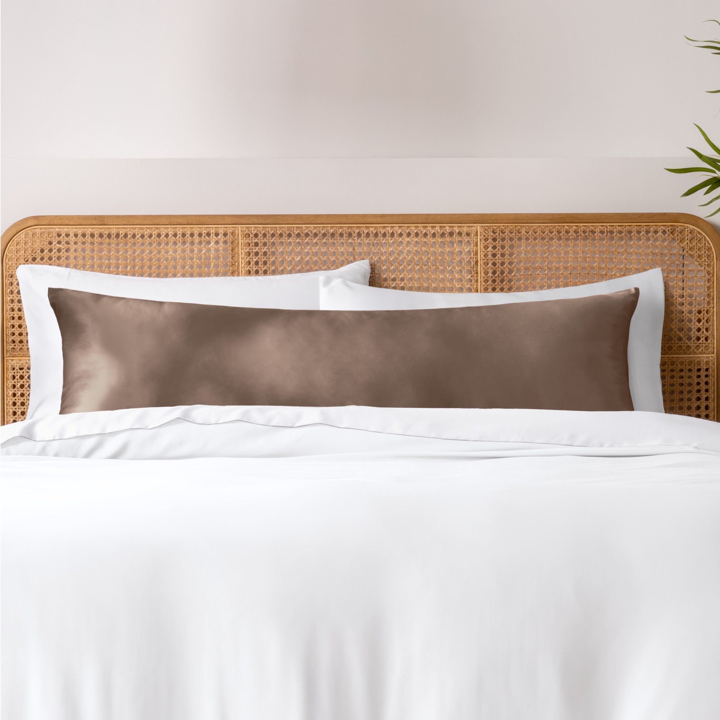 Bamboo body pillowcase on a bed with white bedding and a wicker headboard.
