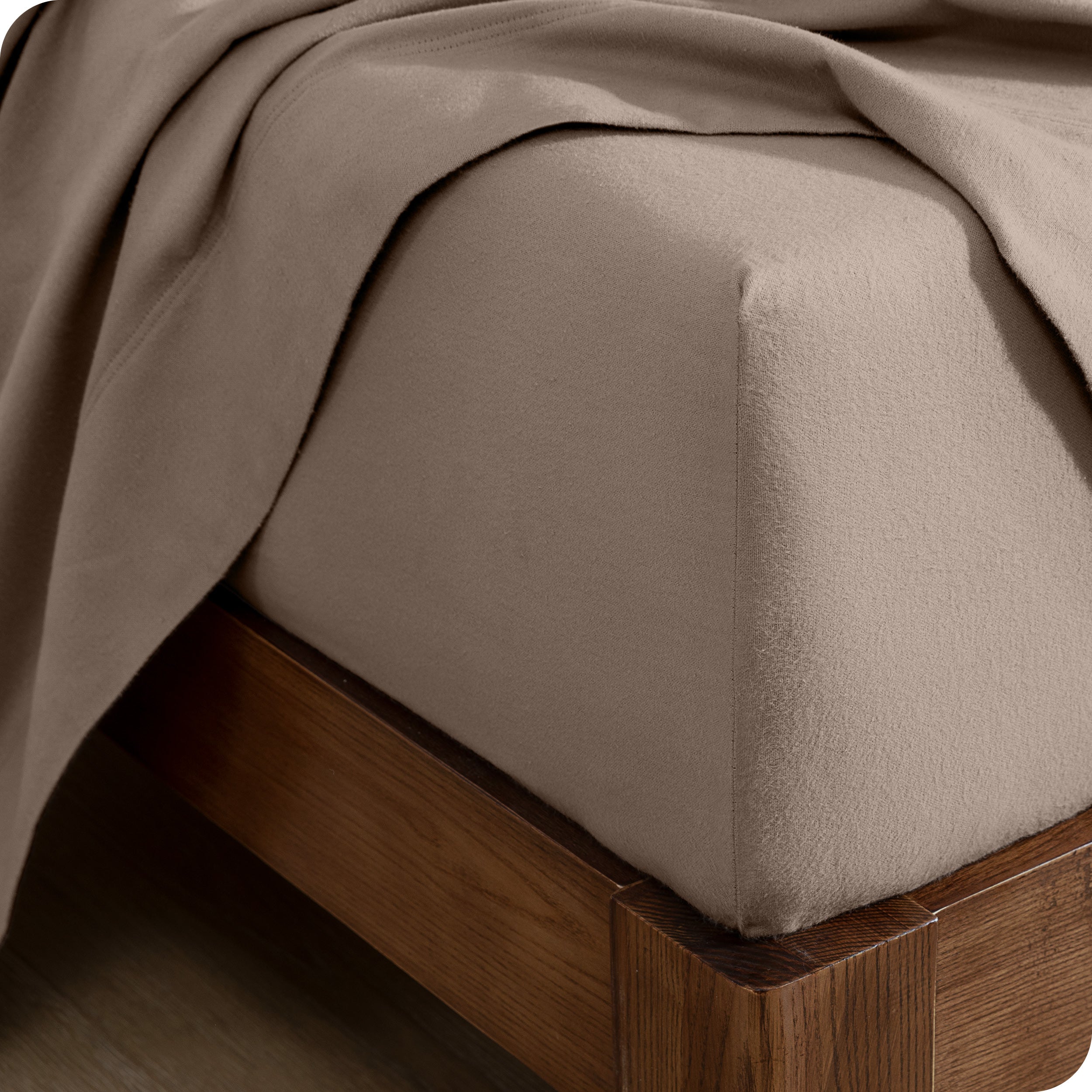 Close up of the corner of a mattress with a fitted sheet and flat sheet on it