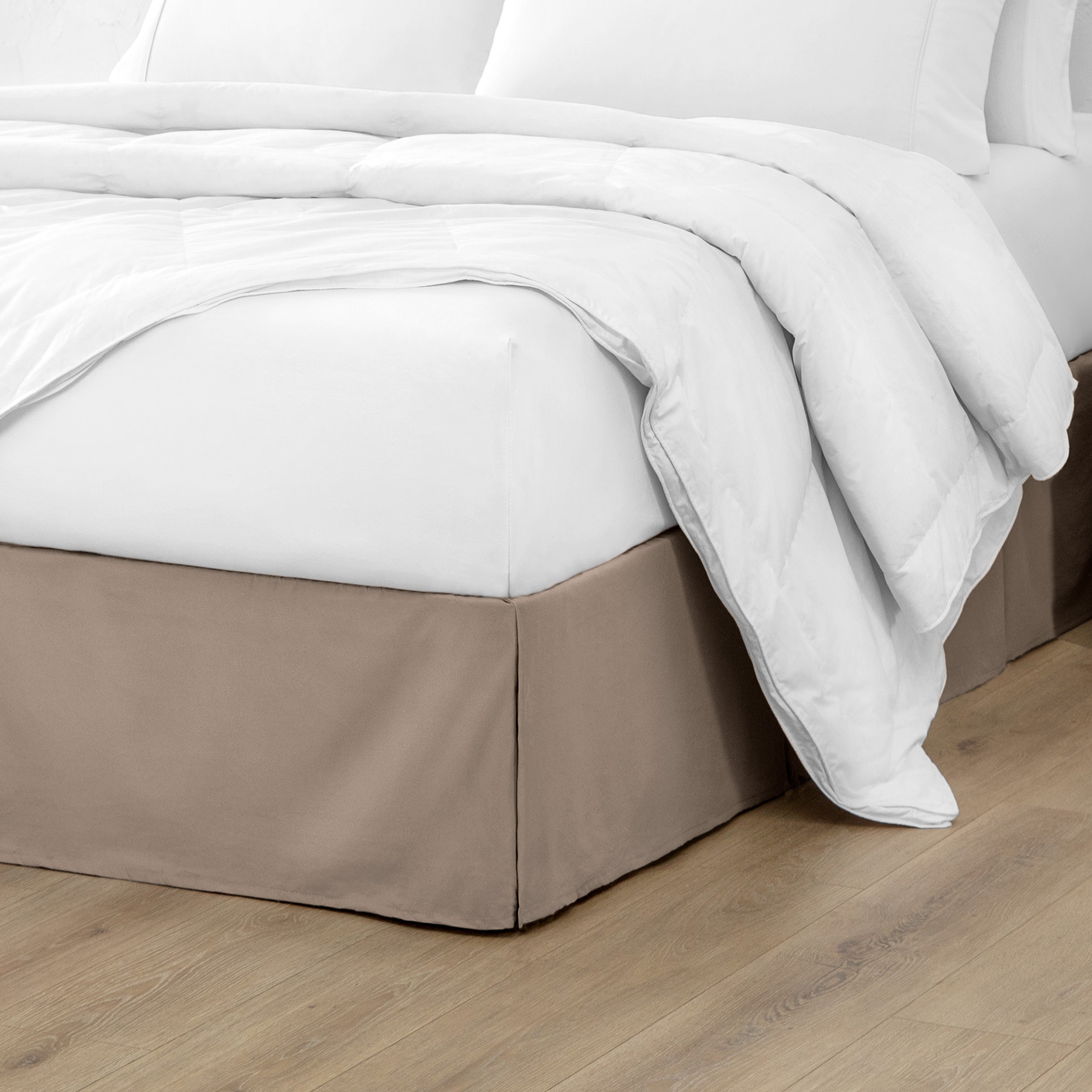 The corner of a bed with a bed skirt and comforter on it