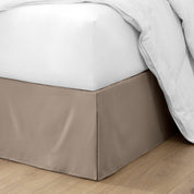 The corner of a bed with a bed skirt and comforter on it